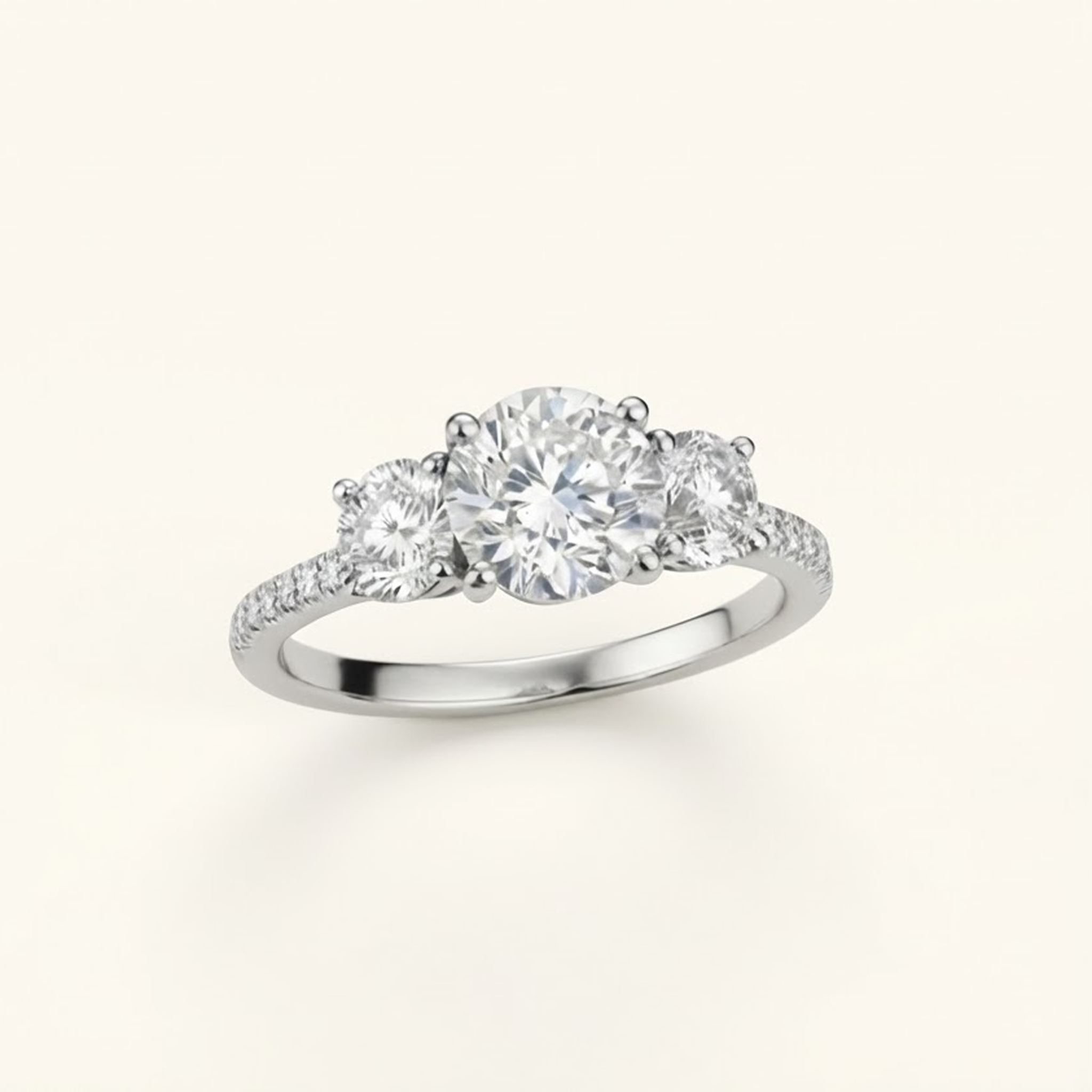 Celia Ring in silver or platinum at an angle, showing the round center diamond, two side stones, and pavé band, on a cream background.

variant: silver