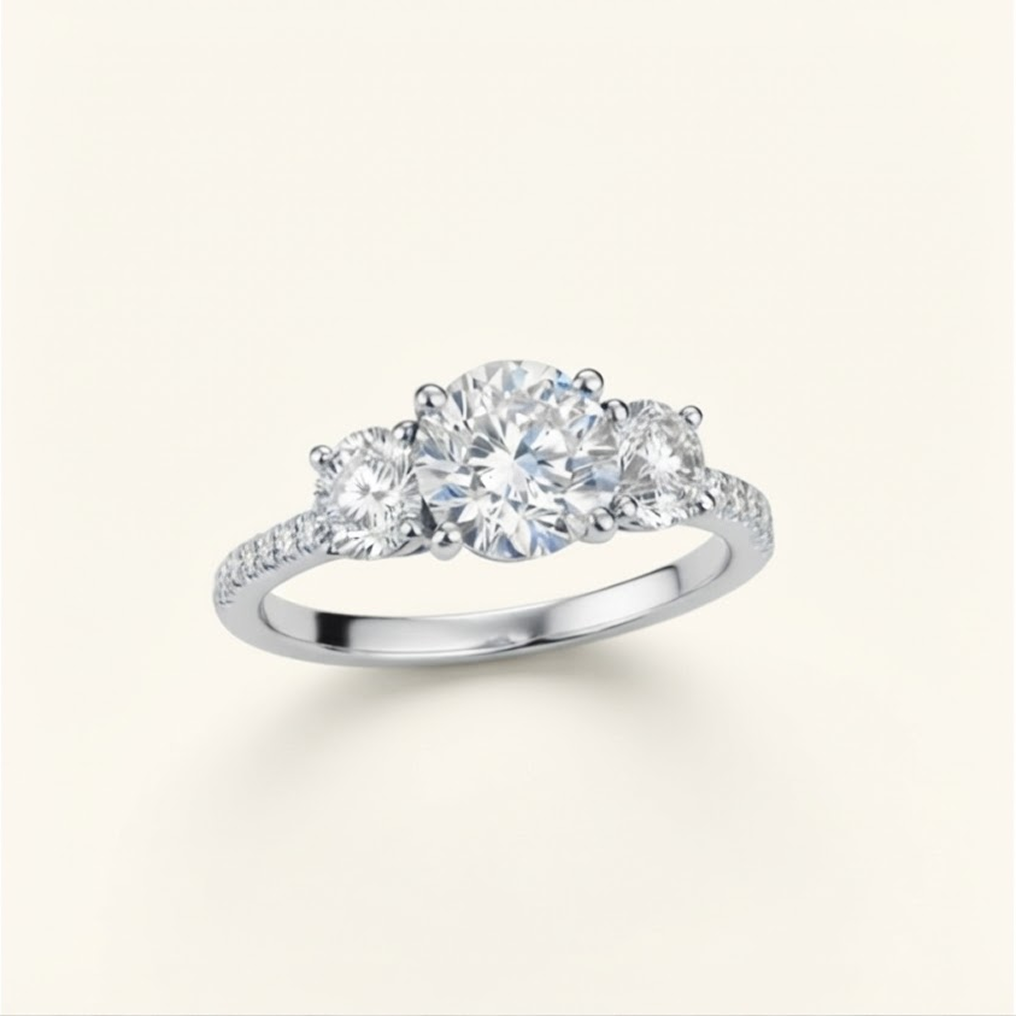 Celia Ring in white gold at an angle, showing the round center diamond, two side stones, and pavé band, on a cream background.

variant: white-gold