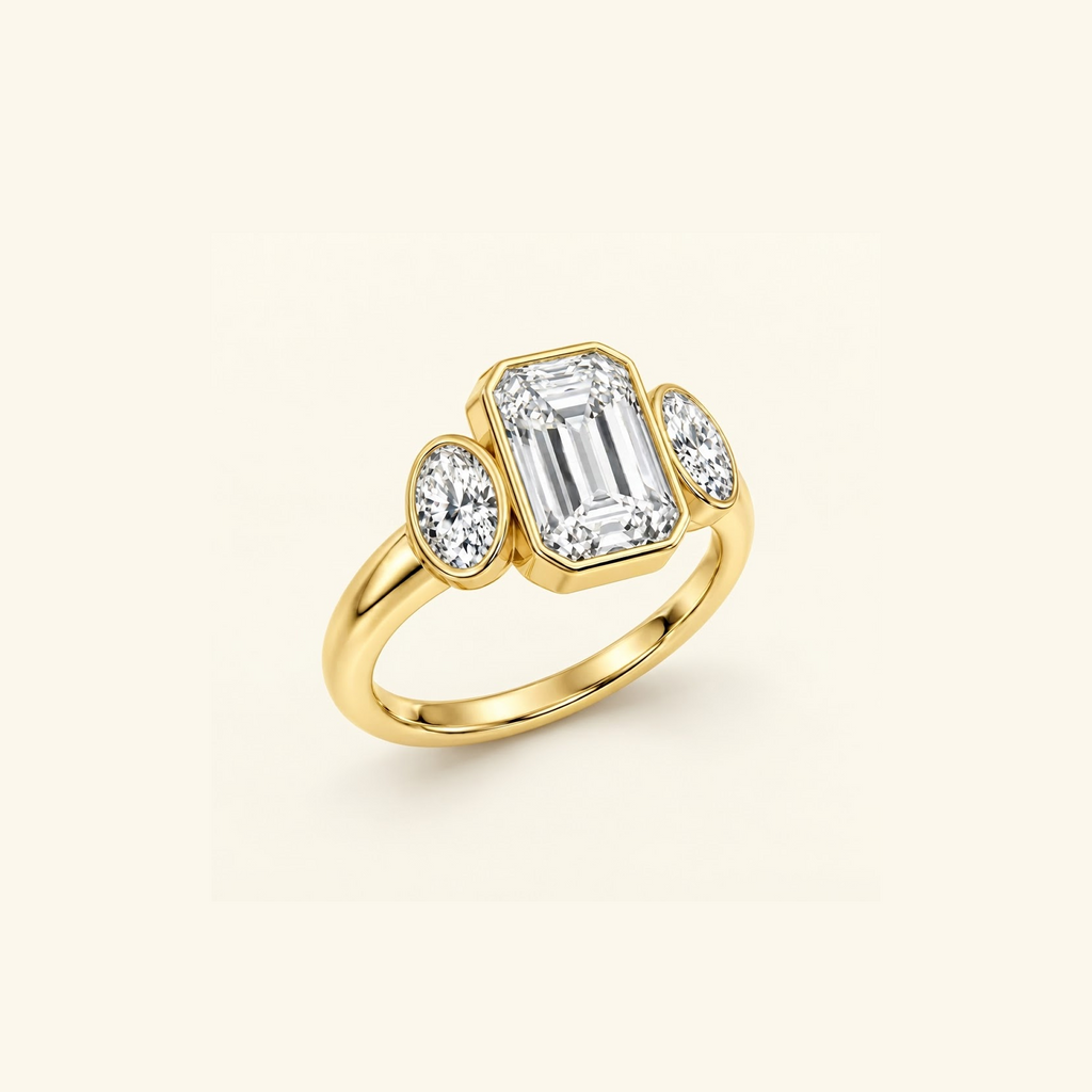 Clio Three-Stone ring in 14K yellow gold at an angle, showing the bezel framing the emerald-cut center
variant: yellow-gold