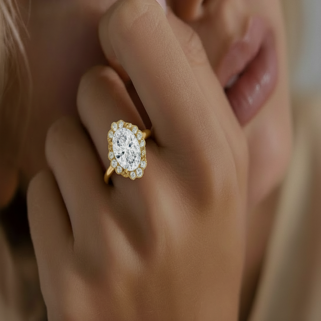 Elise Ring in yellow gold, an oval halo engagement ring, worn on a hand held close to the face.

variant: yellow-gold