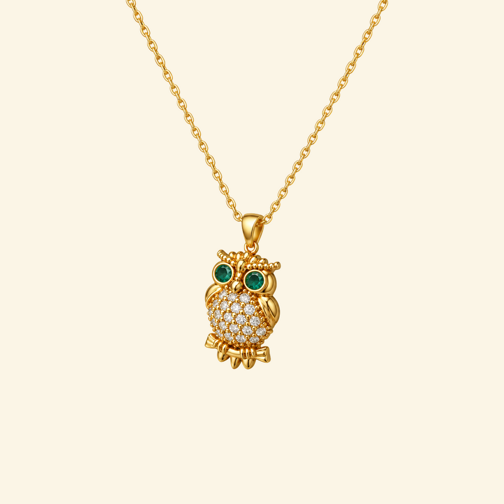 Elowen Necklace in yellow gold, a pavé owl pendant with green stone eyes on a fine cable chain, on a cream background.
variant: yellow-gold