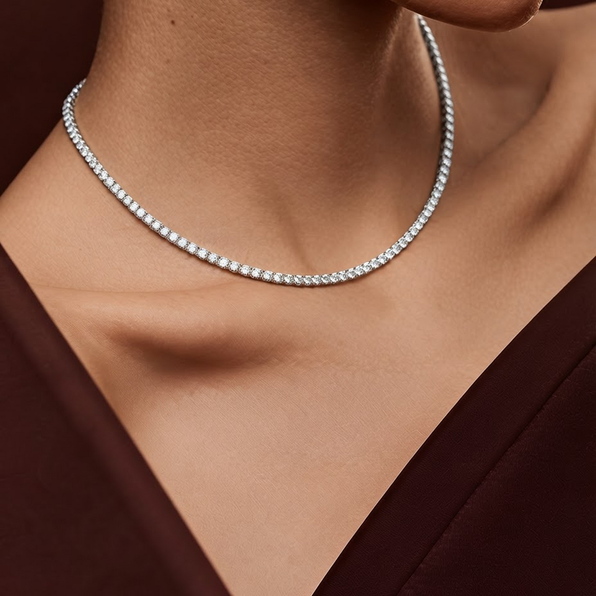 Model wearing the Everly silver diamond tennis necklace at the collarbone with a deep burgundy neckline
variant: silver