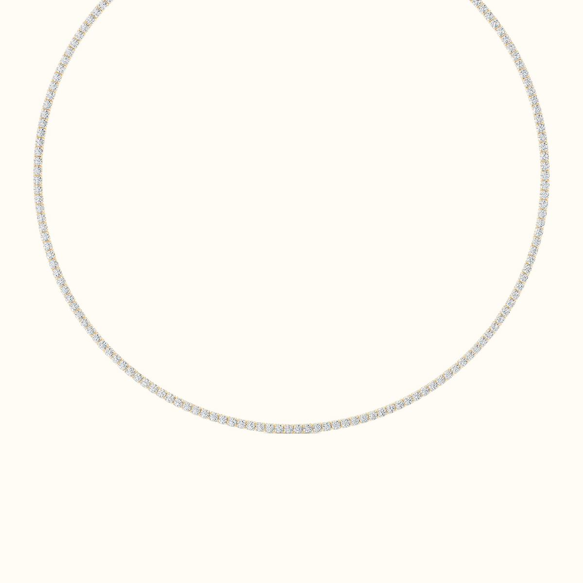 Everly tennis necklace in 14k plated yellow-gold, a single row of round diamonds laid in a circle on a cream background
variant: yellow-gold