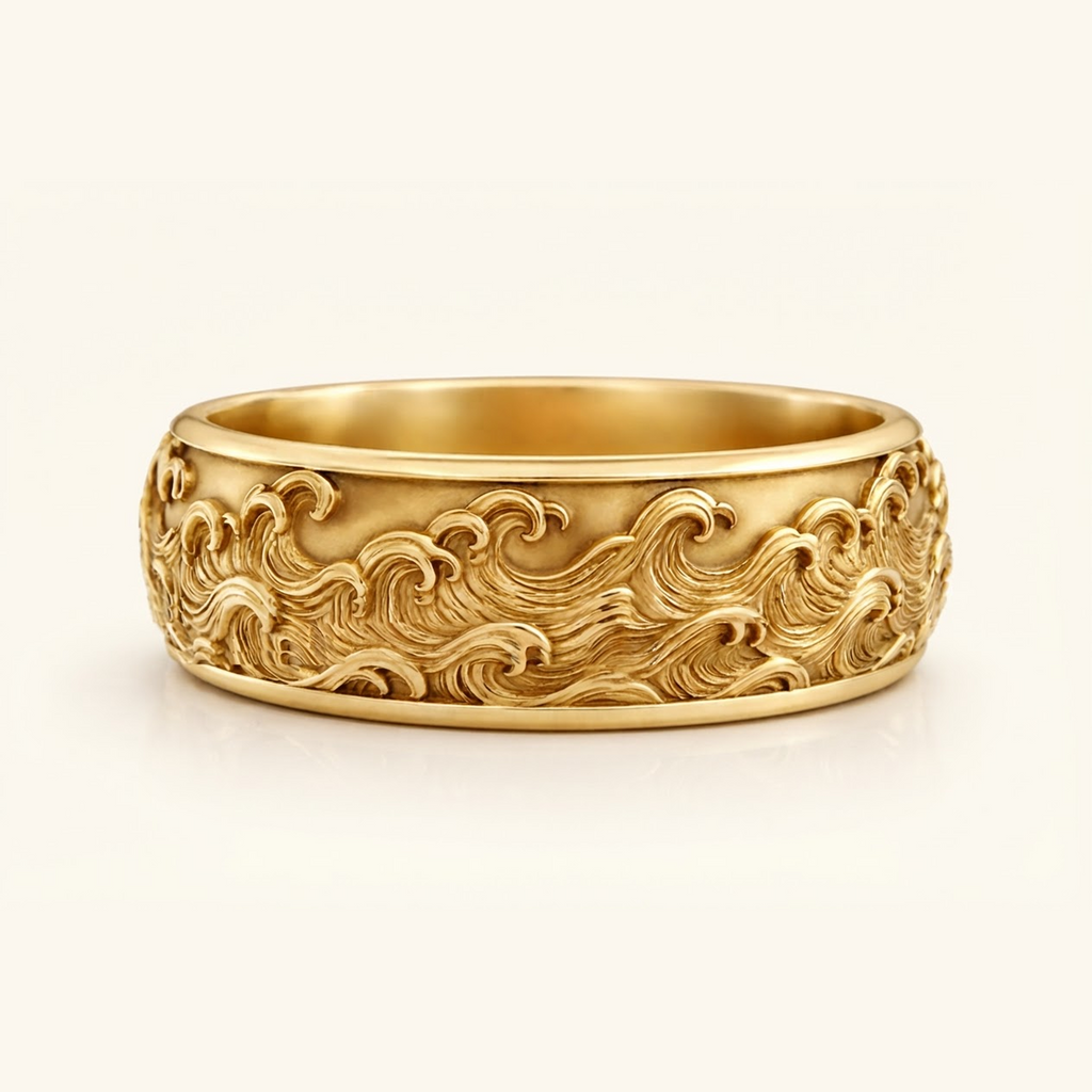 Kai Ring in yellow gold, a wide band with a carved ocean wave relief wrapping the surface, on a cream background.
variant: yellow-gold