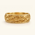 Kai Ring in yellow gold, a wide band with a carved ocean wave relief wrapping the surface, on a cream background.
variant: yellow-gold