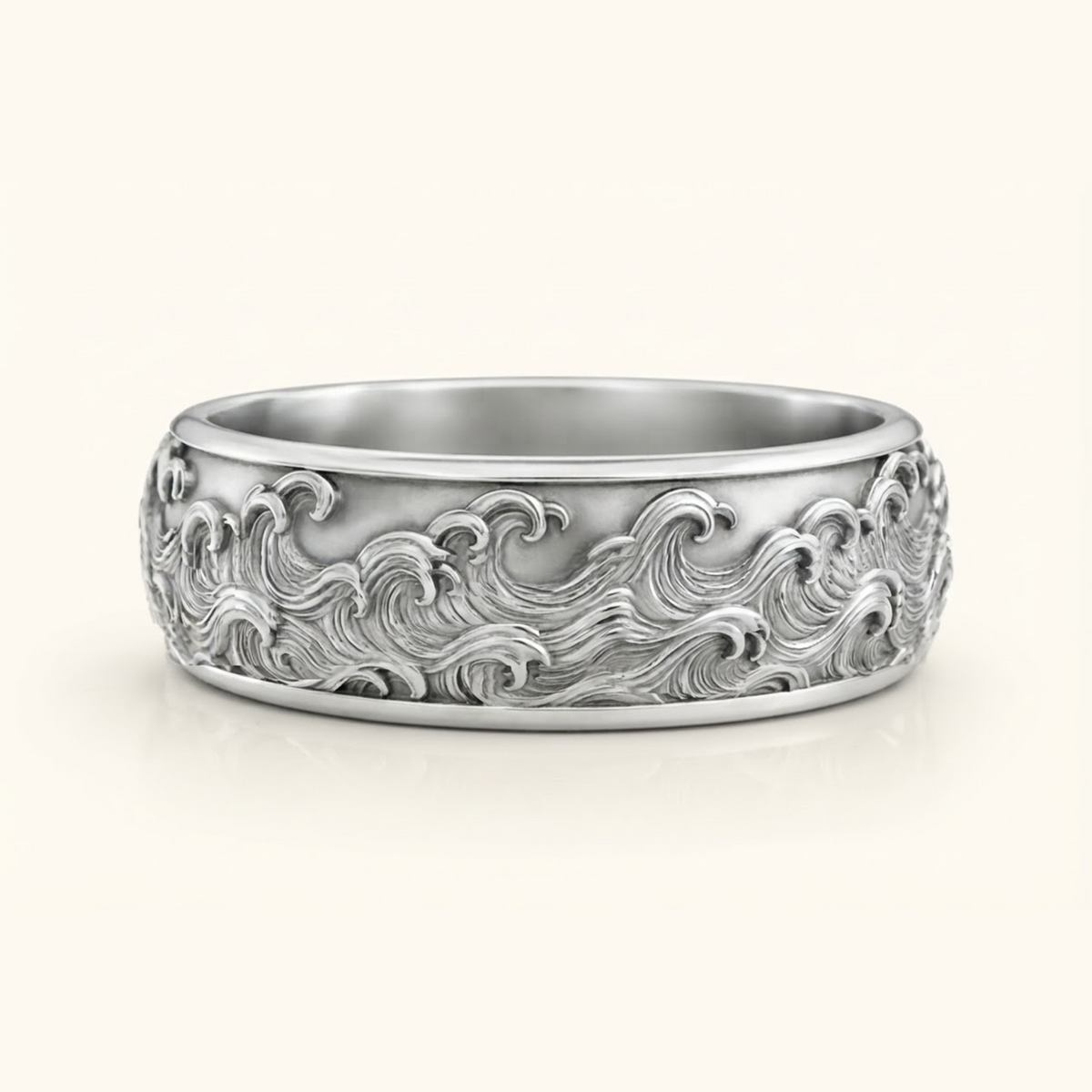Kai Ring in white gold, a wide band with a carved ocean wave relief wrapping the surface, on a cream background.
variant: white-gold