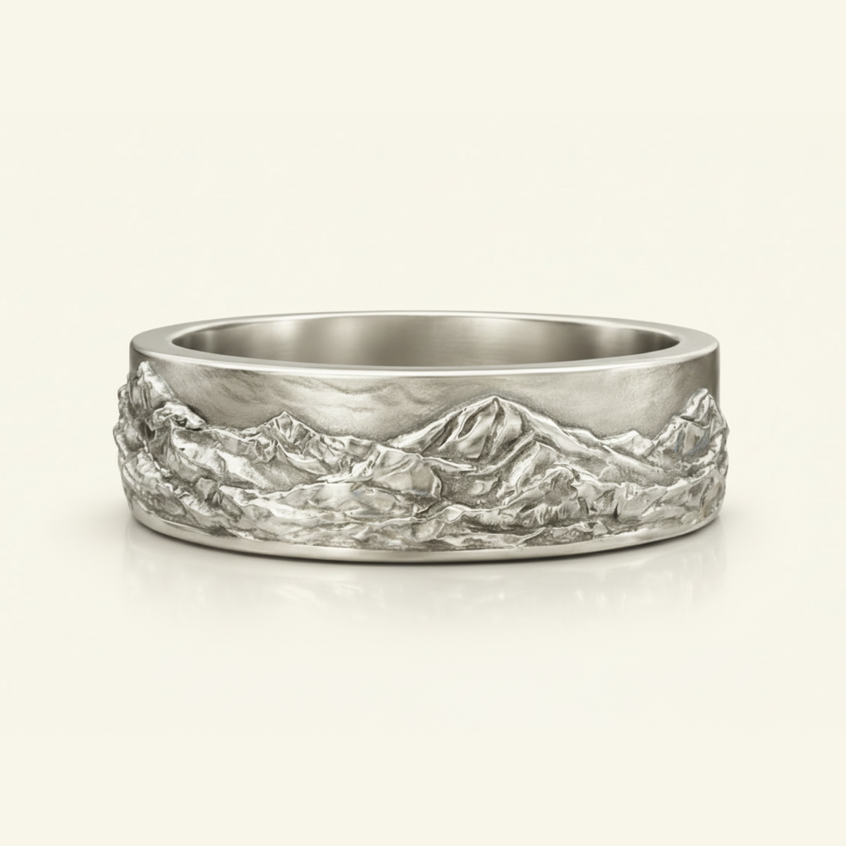 Magnus Ring in silver, a wide band with a sculpted mountain landscape relief wrapping the surface, on a cream background.
variant: silver