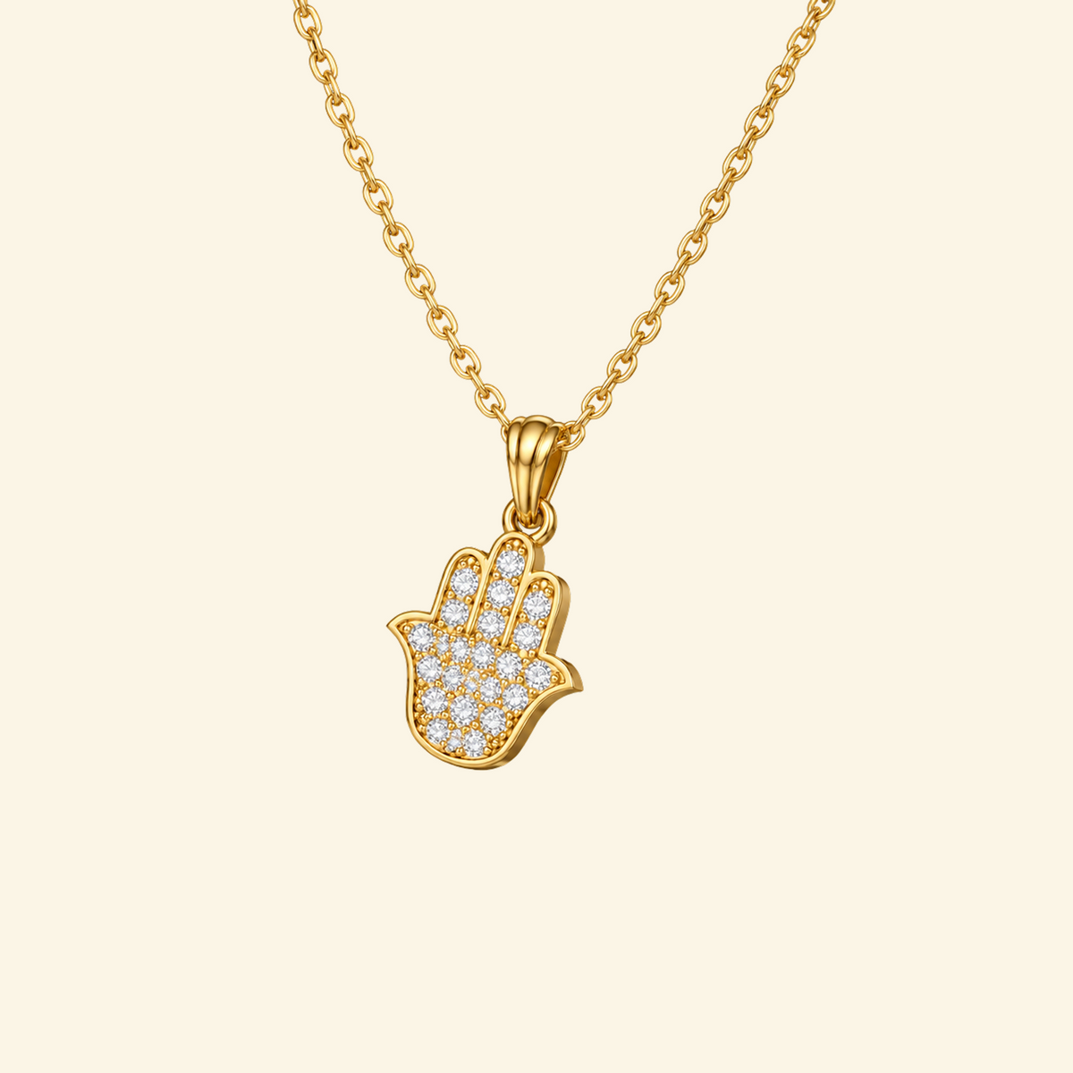 Mira Necklace in yellow gold, a pavé hamsa hand pendant on a fine cable chain, on a cream background.
variant: yellow-gold