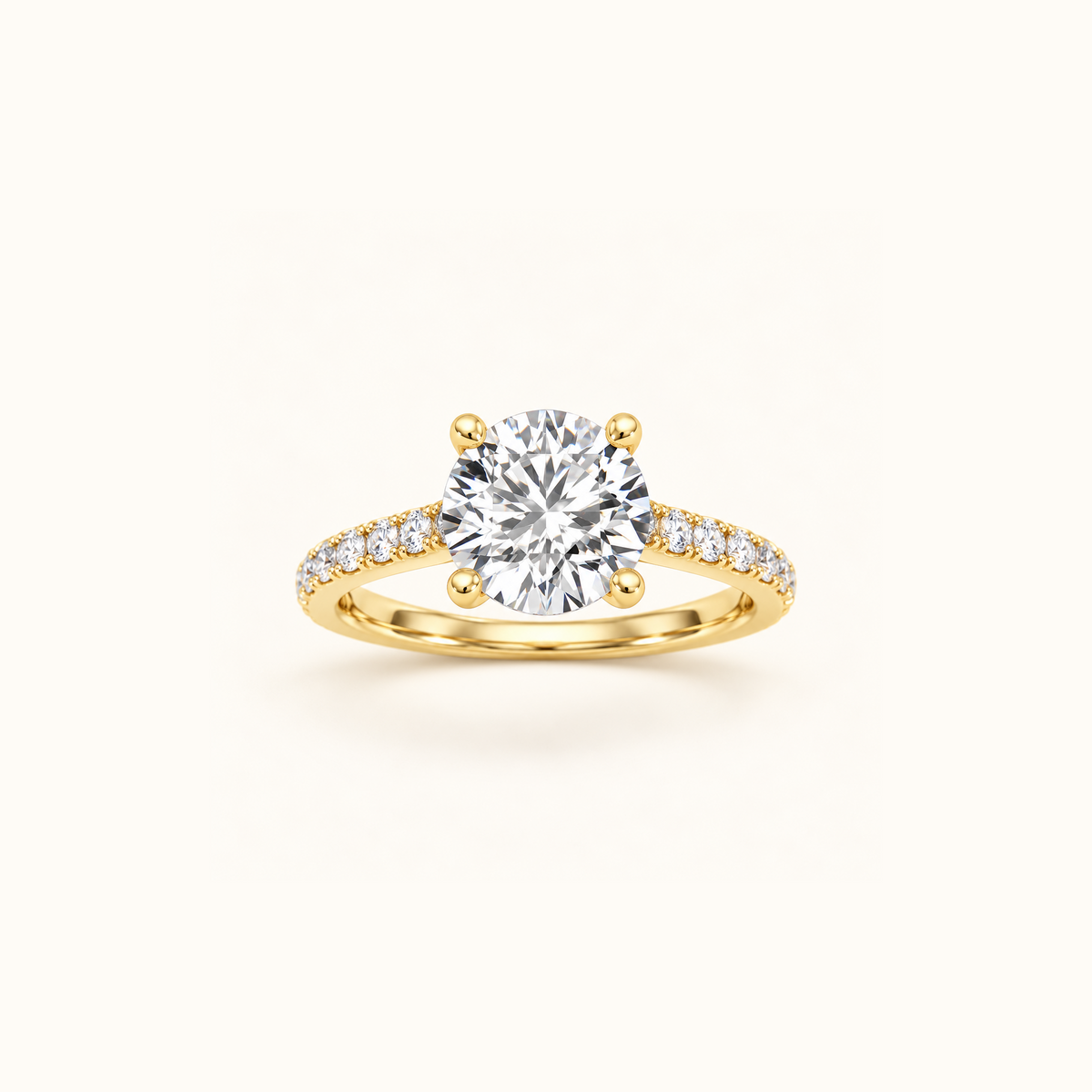 Noelle engagement ring in yellow gold with a round diamond in four claw prongs and a pavé diamond band, on a cream background
variant: yellow-gold