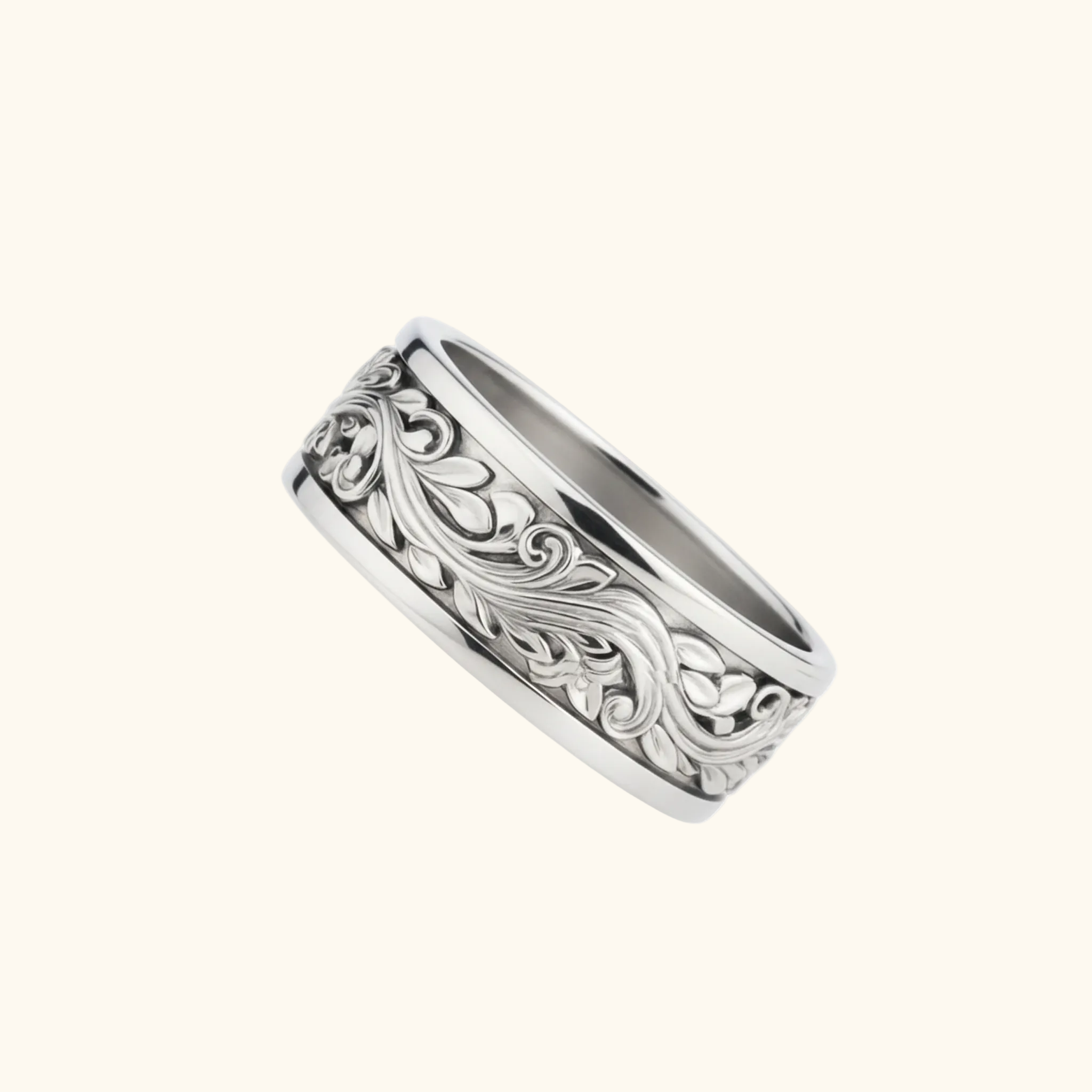 Verona ring in silver, a metal band ring featuring an intricate, raised floral scrollwork pattern on the outer surface, shown against a light cream background.

variant: silver