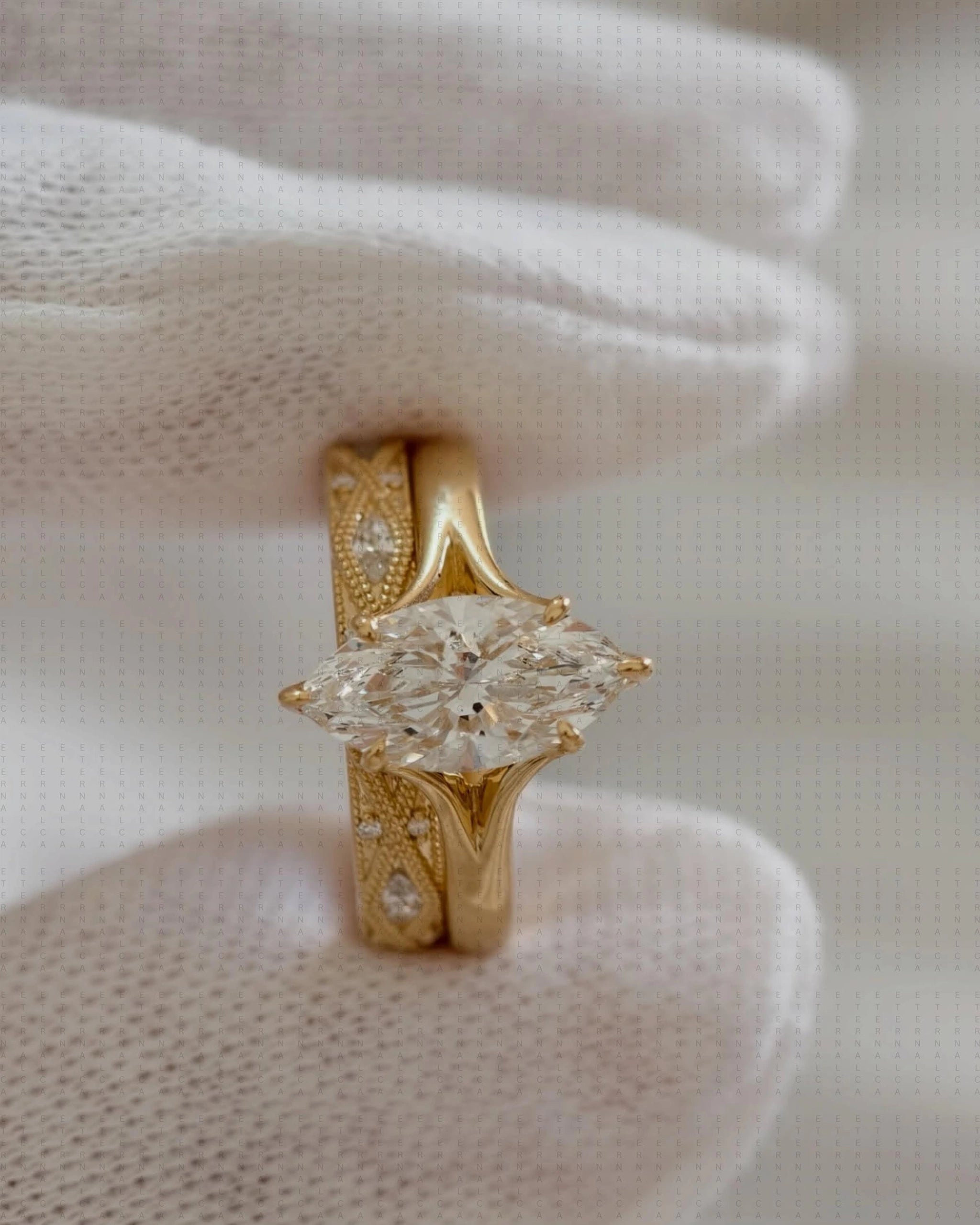Gold marquise diamond engagement ring with milgrain band detail, held in white gloved hands